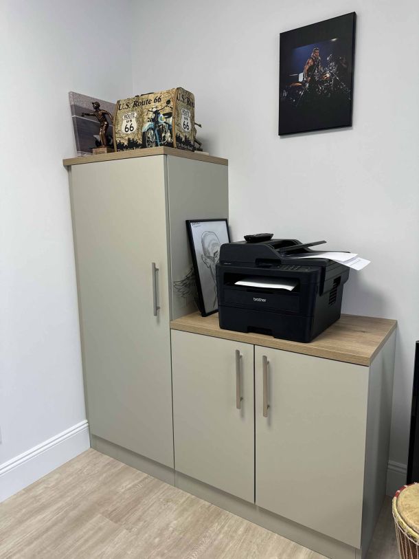 Meubles de rangement sur mesure en finition claire avec un plateau en bois, utilisés dans un bureau, avec une imprimante, des décorations Route 66 et une photo encadrée accrochée au mur.